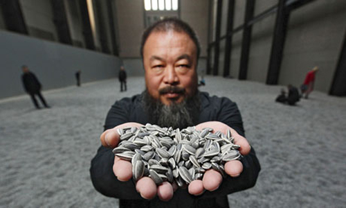 Click the image for a view of: Chinese artist Ai Weiwei at his current exhibition of 100 million ceramic seeds at the Tate Modern
